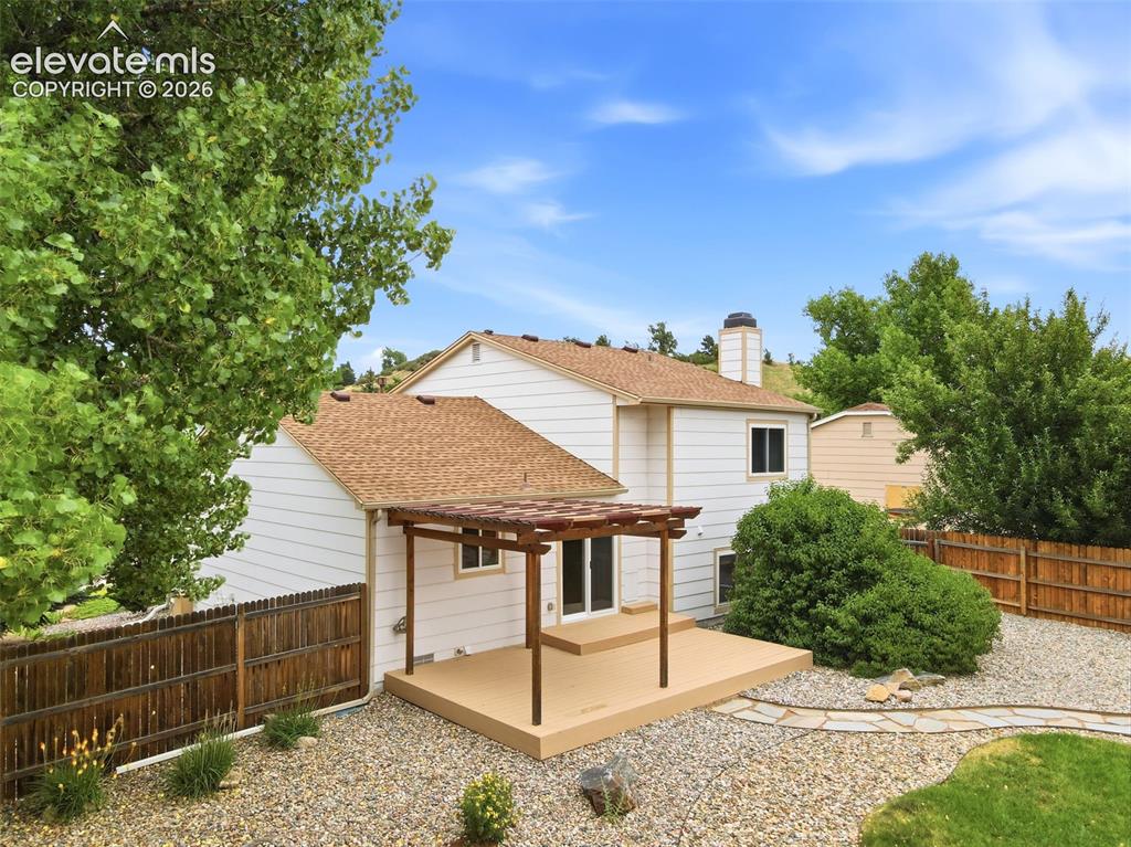 Image 44 of 50: Rear exterior featuring a spacious patio with a pergola, gravel landscaping