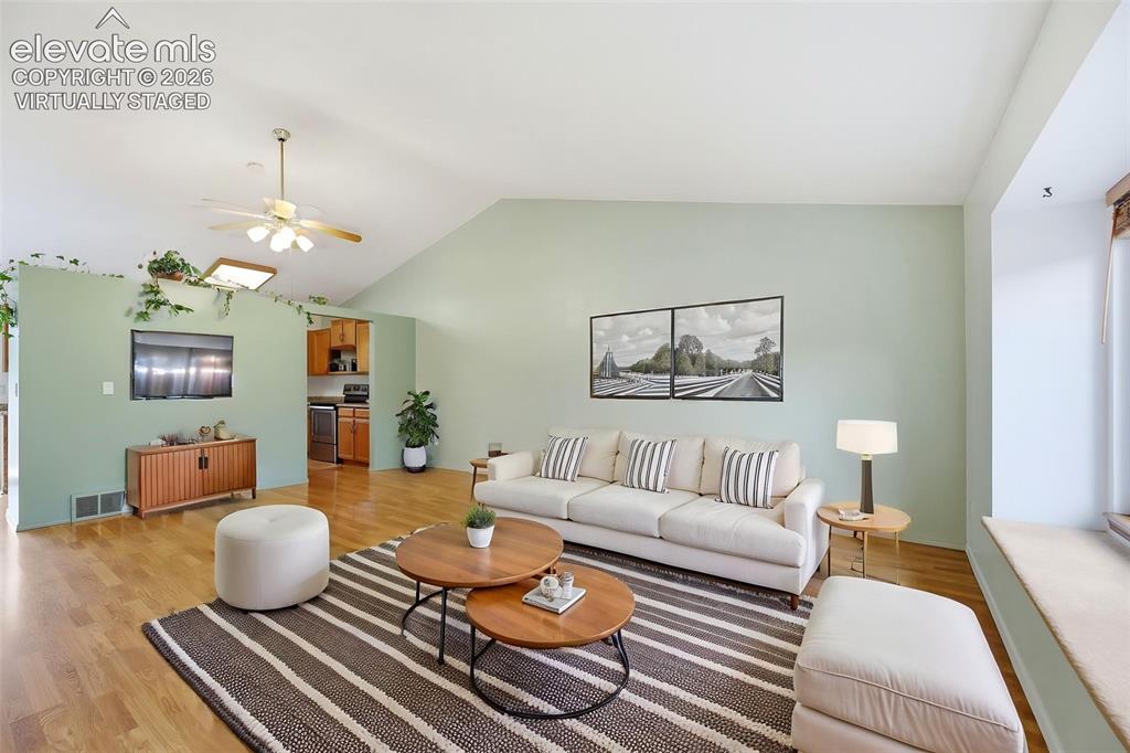 Image 6 of 50: Virtually Staged - Spacious living area featuring vaulted ceilings, wood-fi
