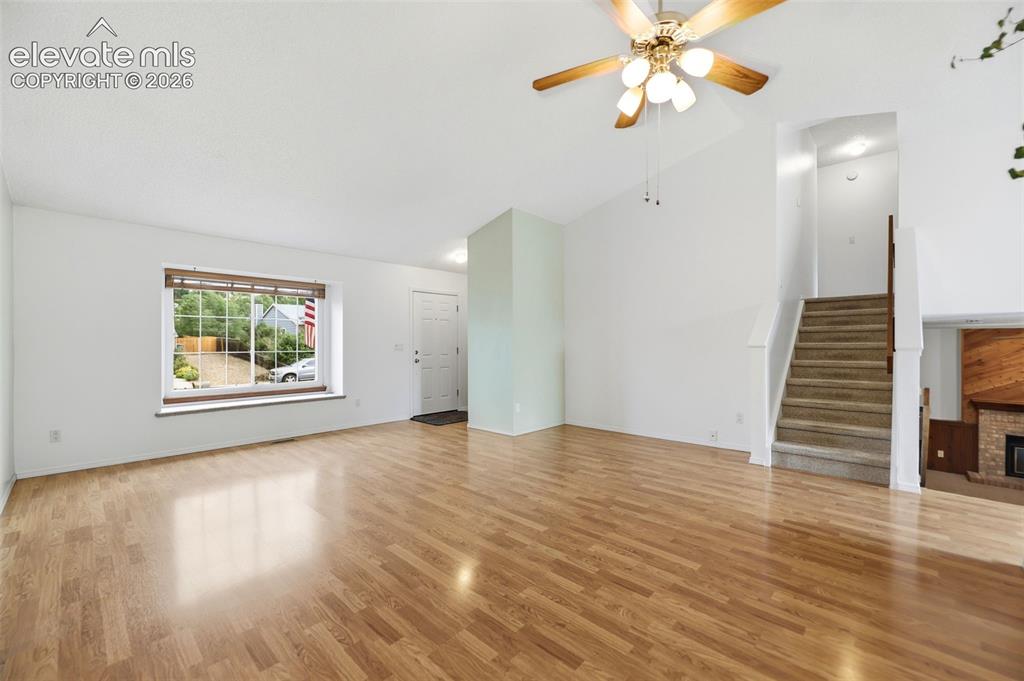 Image 8 of 50: Spacious living area featuring wood-finish flooring, a large picture window