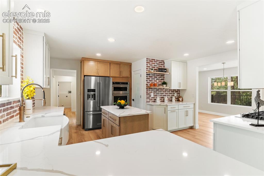 Image 13 of 43: Kitchen featuring light wood-style flooring, light stone countertops, open 