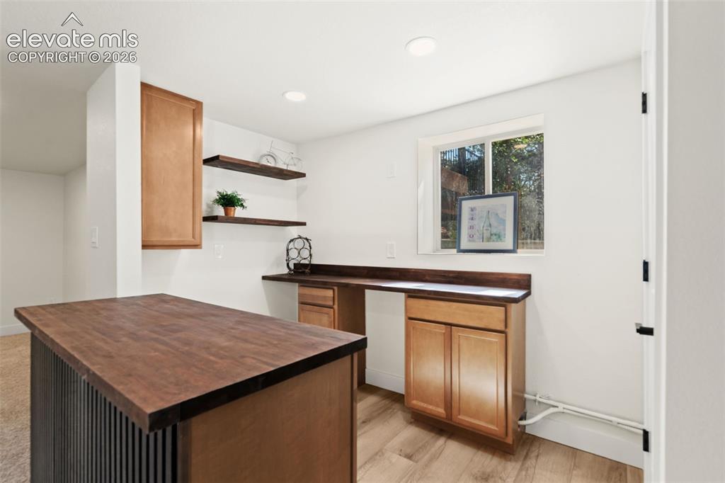 Image 32 of 43: Kitchen featuring butcher block counters, open shelves, brown cabinets, lig