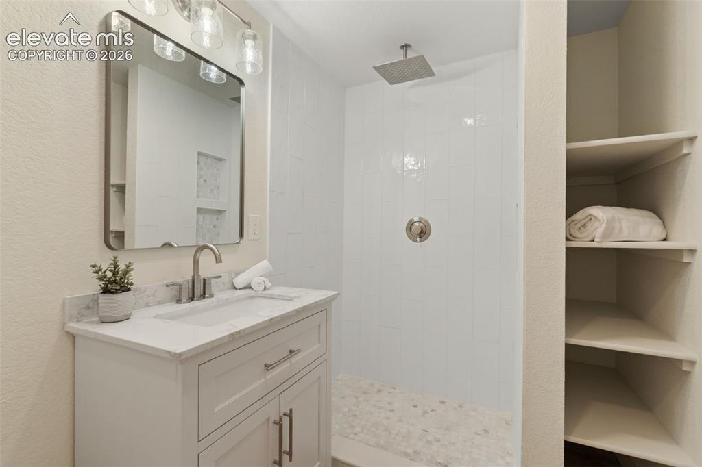 Image 34 of 43: Full bath with vanity, a walk in shower, and a textured wall