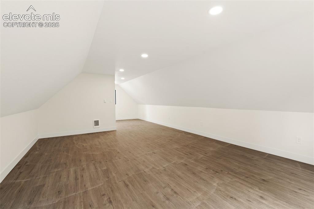 Image 40 of 43: Additional living space featuring dark wood-style flooring, lofted ceiling,