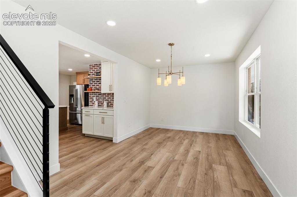 Image 5 of 43: Unfurnished dining area with stairway, a chandelier, light wood-type floori