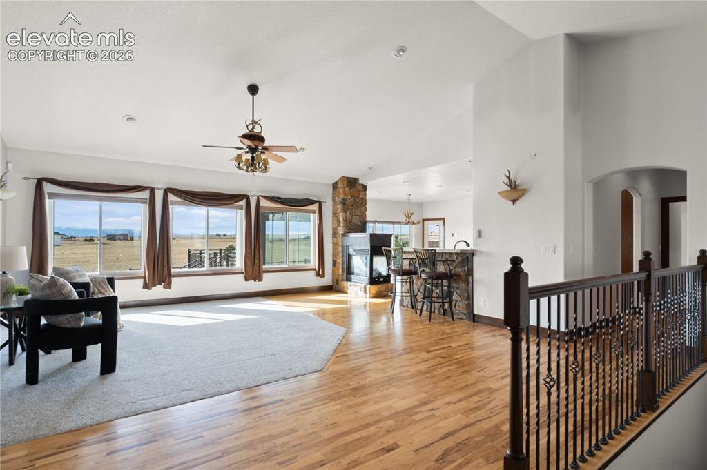Image 10 of 40: Open living room and kitchen with three-sided fireplace and mountain views