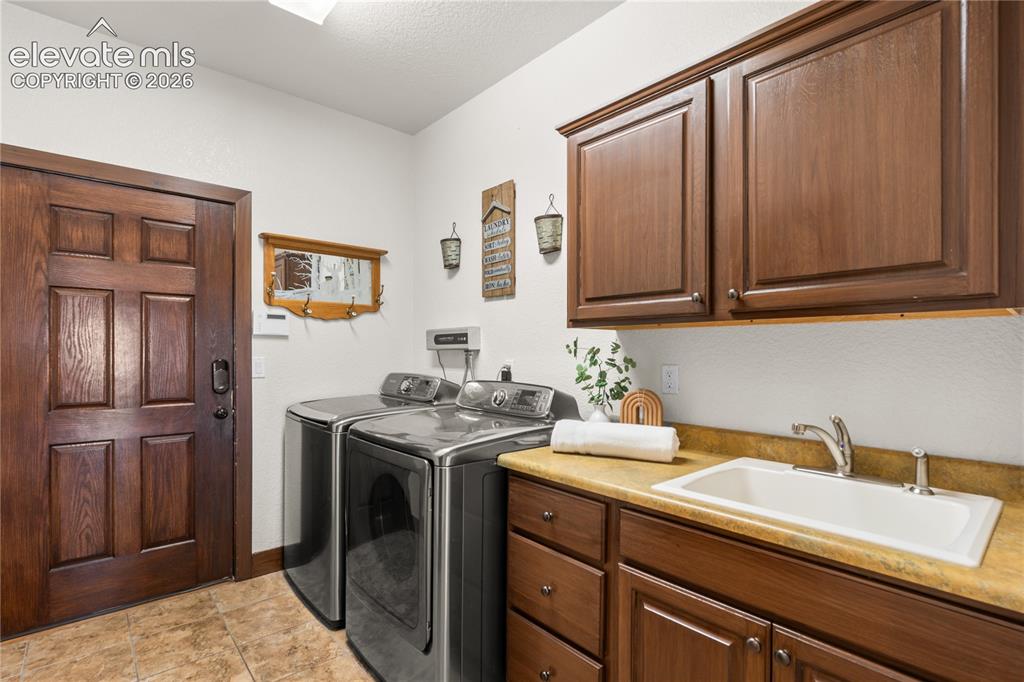 Image 28 of 40: The laundry room exits to the garage and hosts a powder bath, utility sink,