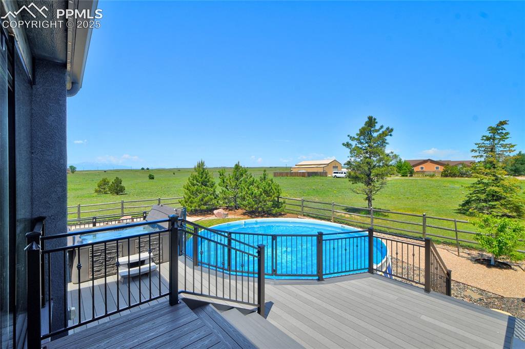 Image 7 of 40: A generous composite deck with railings, a above ground pool and hot tub...