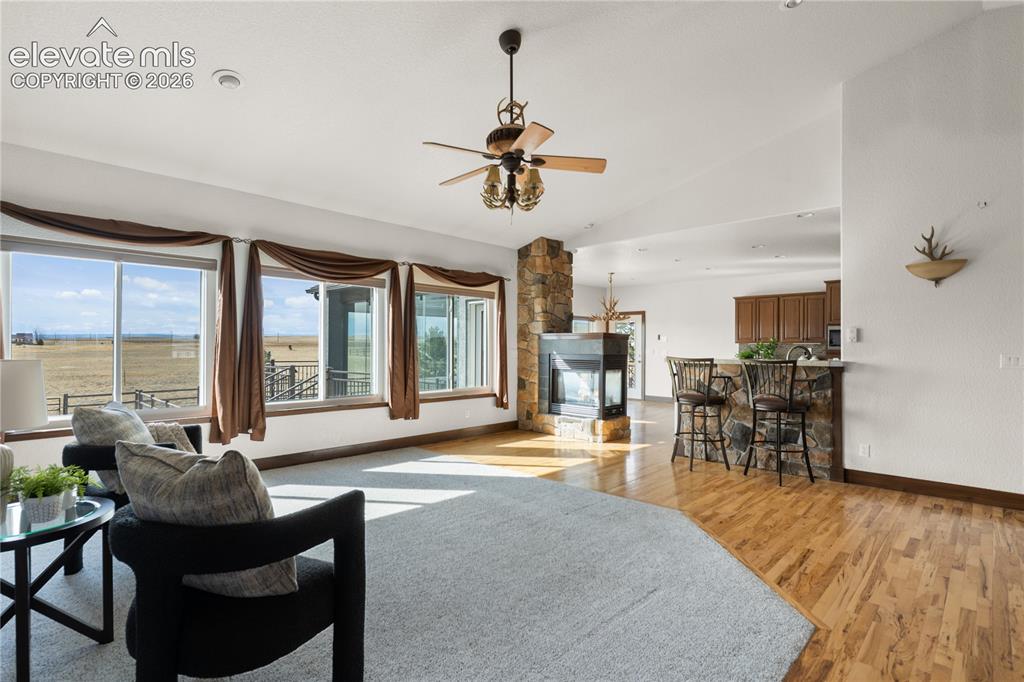 Image 8 of 40: Open-concept living room with triple-sided fireplace, seamless flow to the