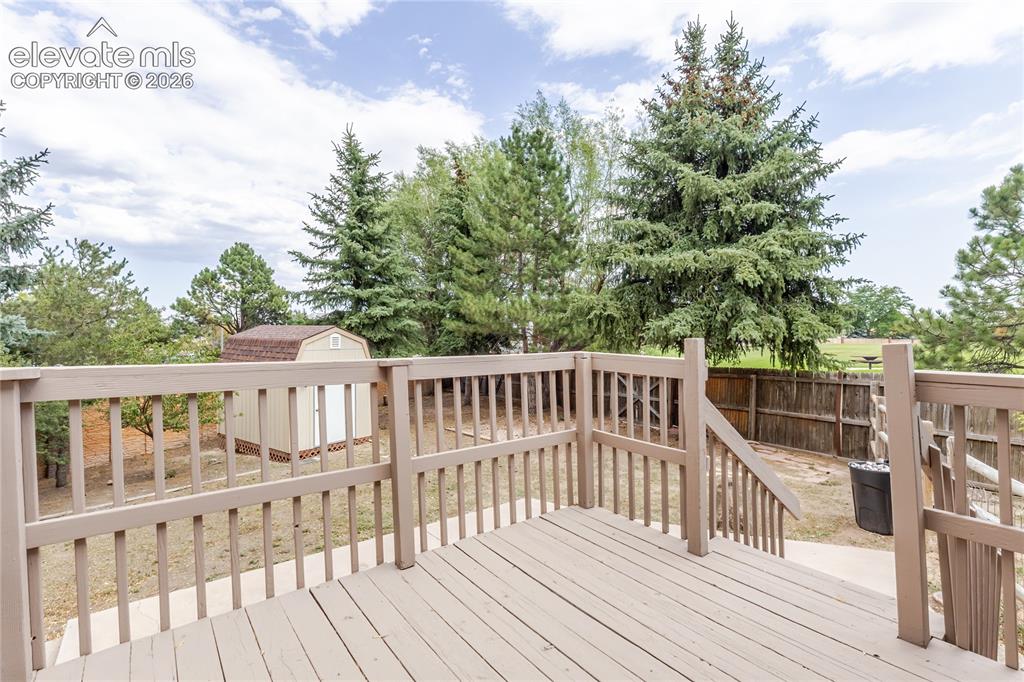 Image 10 of 46: Wood-finish deck with railing and integrated steps, featuring an exterior s