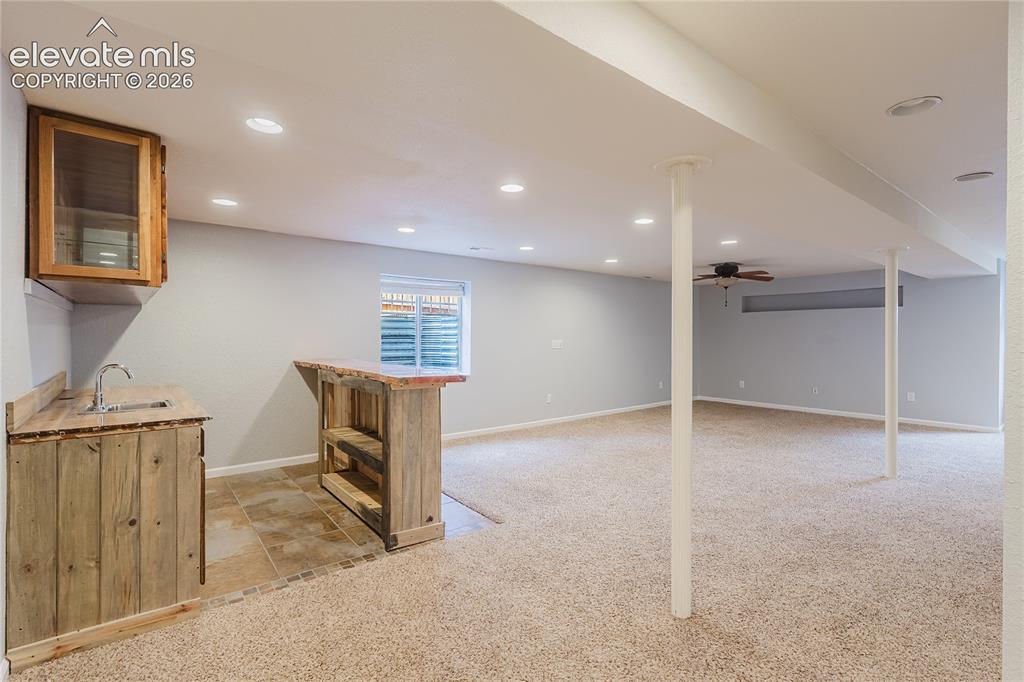 Image 13 of 46: Finished lower level featuring a wet bar with rustic wood-finish cabinetry,