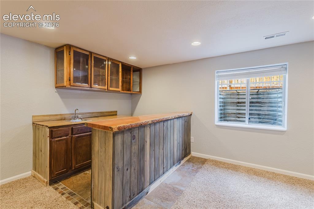 Image 16 of 46: Wood-finish wet bar with built-in cabinetry, integrated sink, and recessed