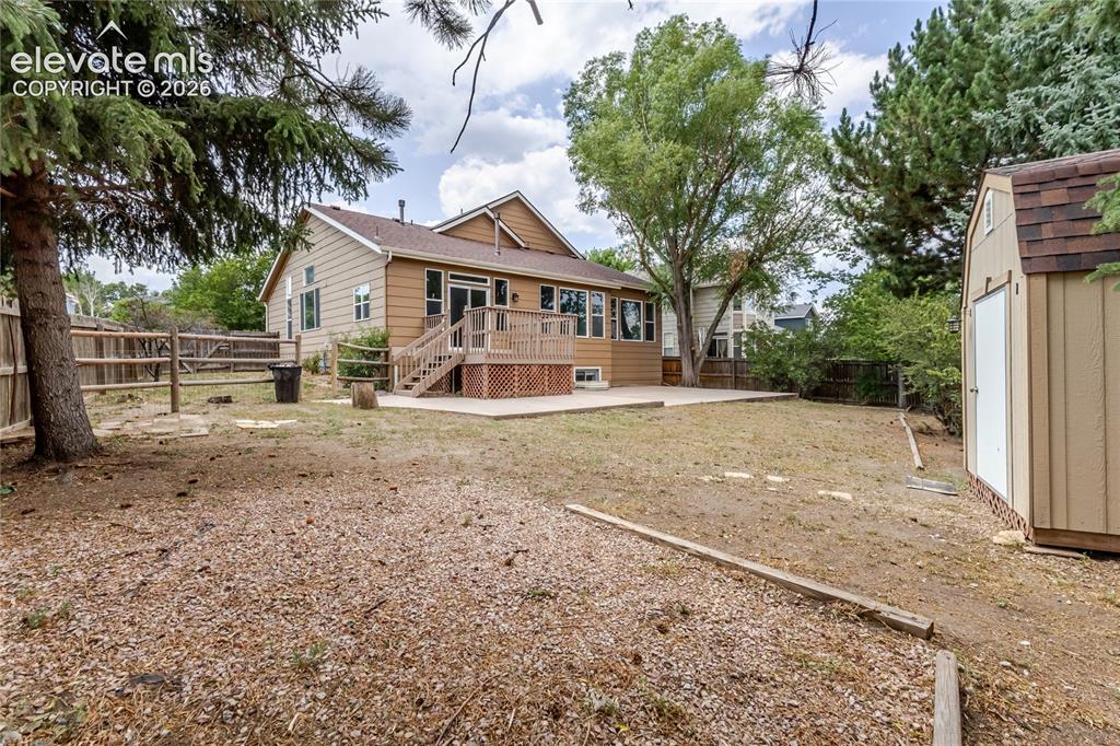 Image 2 of 46: Backyard featuring a wood deck, concrete patio, and storage shed