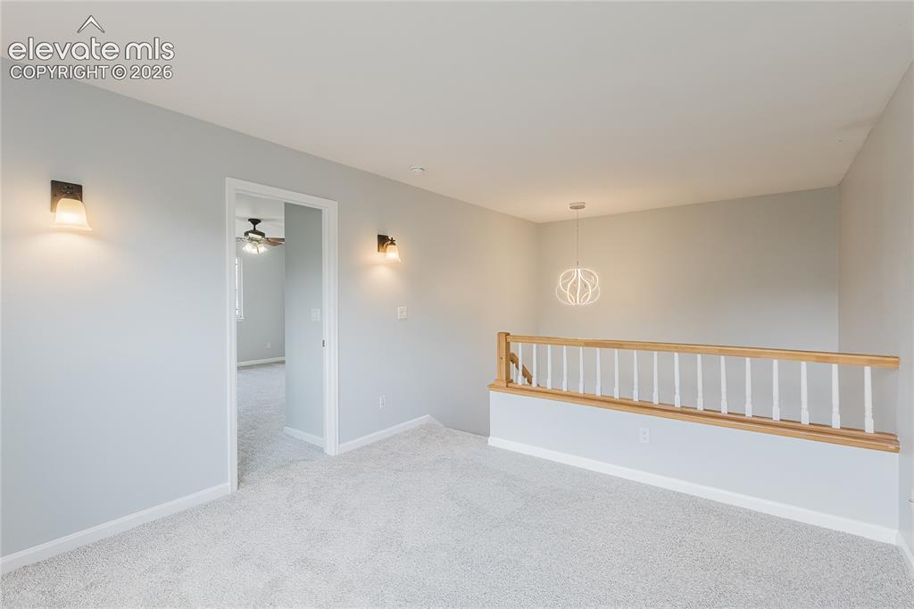 Image 21 of 46: Neutral carpeting, wood handrail with white balusters, and contemporary pen
