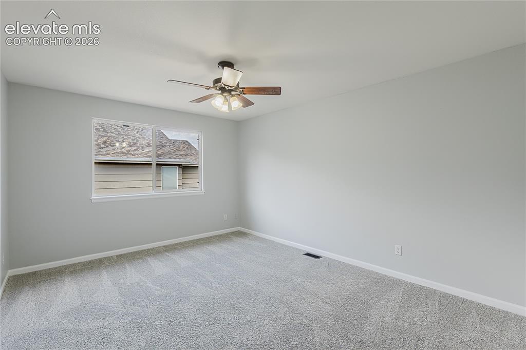 Image 22 of 46: Neutral-toned walls with light grey carpeting, complemented by a ceiling fa