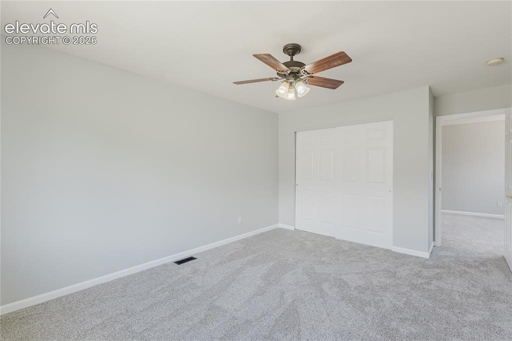 Image 23 of 46: Plush carpet flooring, neutral wall paint, ceiling fan with light fixture, 