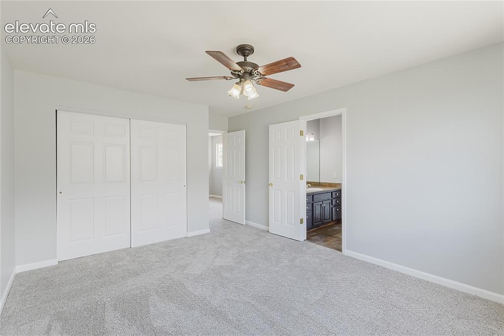 Image 25 of 46: Carpeted room with a ceiling fan, bifold closet doors, and a doorway to a b