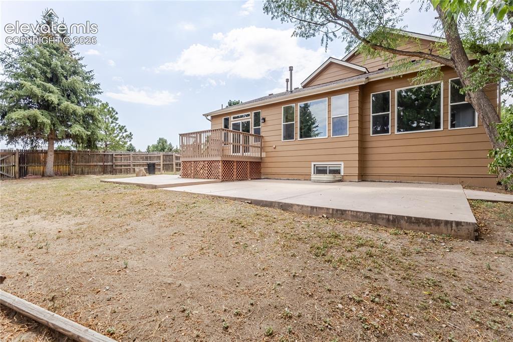 Image 3 of 46: Expansive backyard featuring a wood privacy fence, concrete patio, and a ra