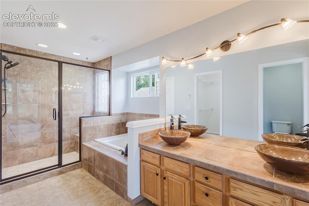 Image 42 of 46: Spacious bath featuring a walk-in shower with tile surround, built-in soaki