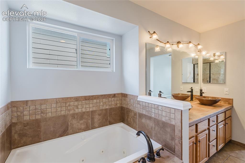 Image 43 of 46: Spa-inspired primary bathroom featuring dual vanities with wood cabinetry, 