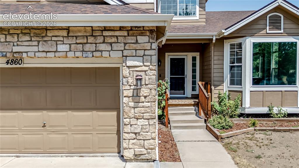 Image 45 of 46: Stone veneer exterior accenting a panel garage door