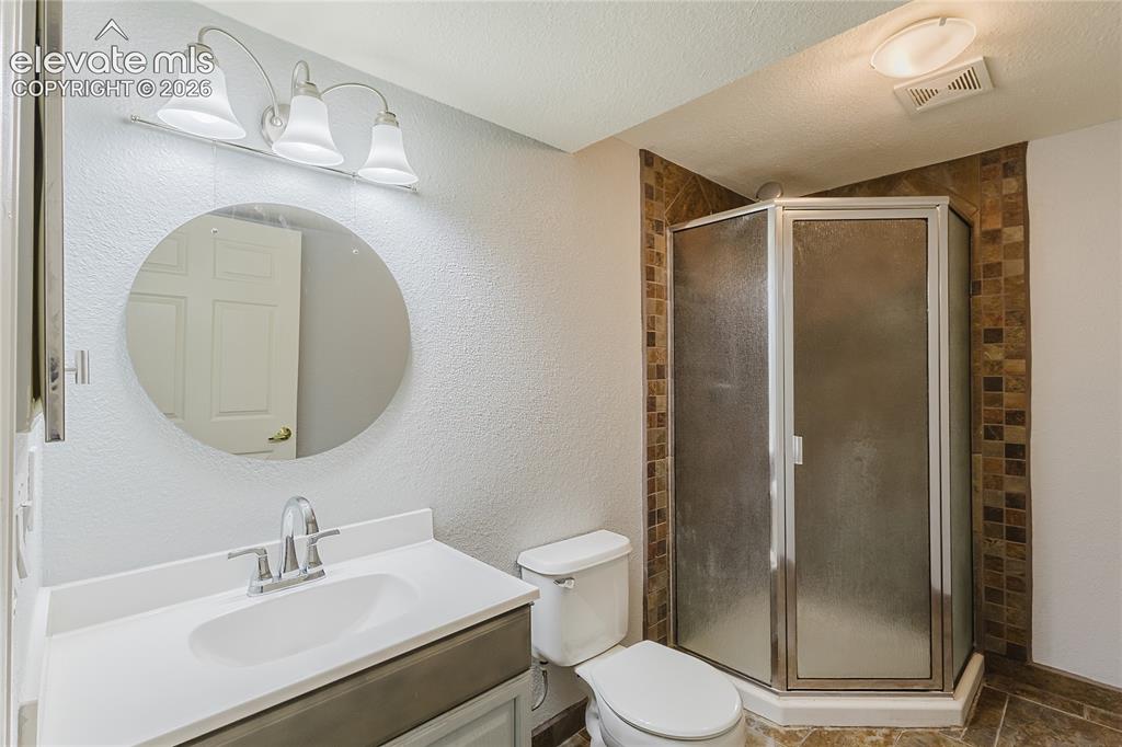 Image 6 of 46: Basement bathroom featuring a circular framed mirror with integrated vanity