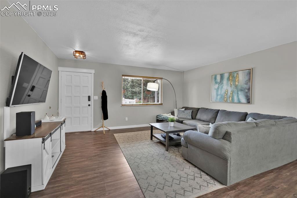 Image 15 of 50: Living area with dark wood-style flooring and a textured ceiling