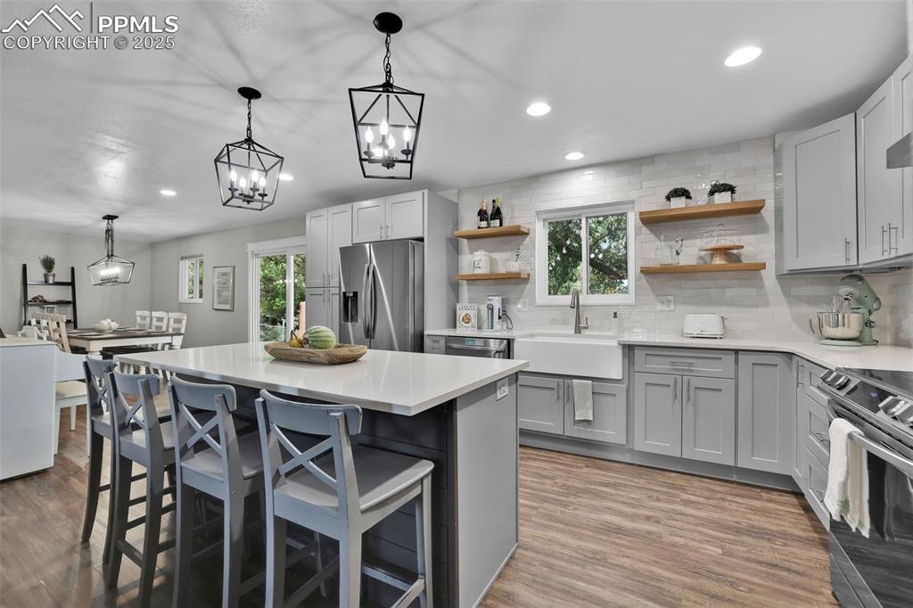 Image 18 of 50: Kitchen featuring recessed lighting, a breakfast bar, backsplash, hanging l