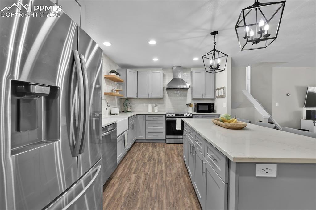 Image 19 of 50: Kitchen with appliances with stainless steel finishes, gray cabinetry, deco