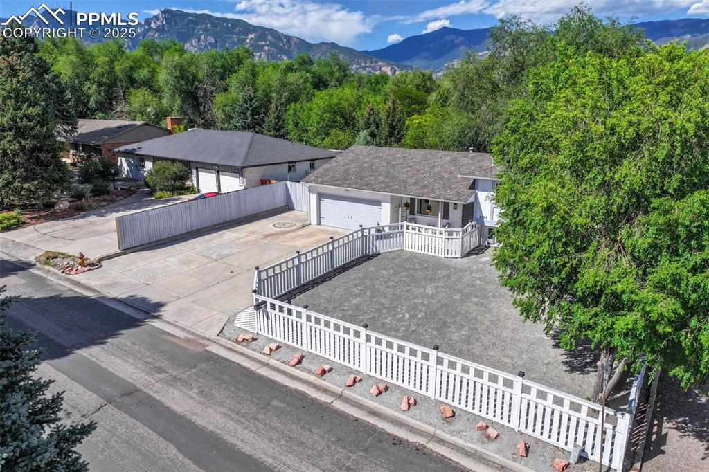Image 2 of 50: Single story home with a garage, driveway, a mountain view, and a fenced fr