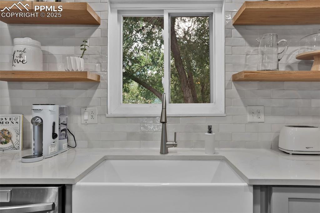 Image 20 of 50: Kitchen view of open shelves, decorative backsplash, and light stone counte
