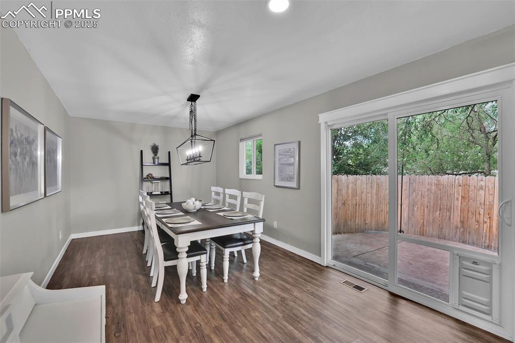 Image 21 of 50: Dining space with dark wood-type flooring and a chandelier