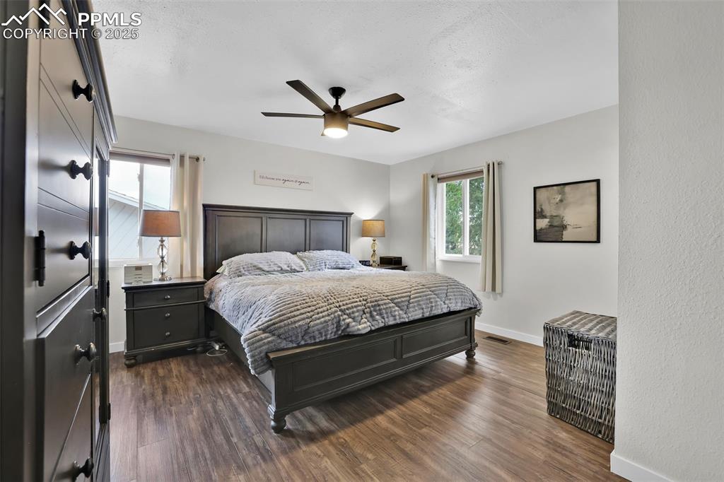 Image 24 of 50: Bedroom with dark wood finished floors, a ceiling fan, and a textured ceili