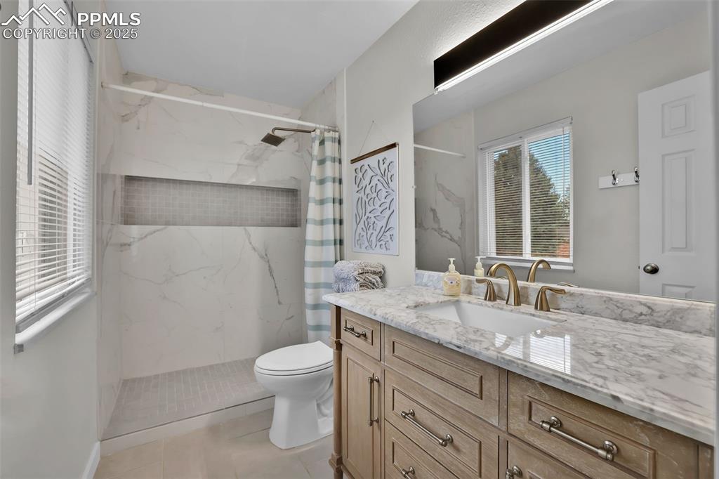 Image 26 of 50: Full bath with vanity, a marble finish shower, and light tile patterned flo
