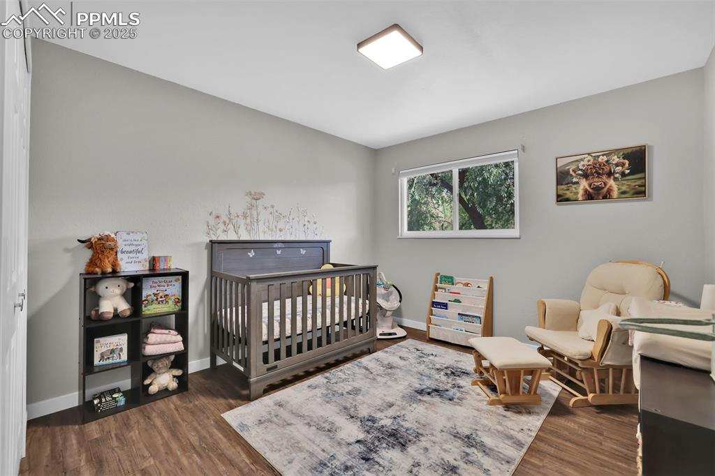 Image 27 of 50: Bedroom featuring a nursery area and dark wood-type flooring