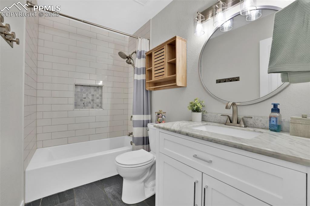 Image 31 of 50: Bathroom featuring shower / bath combination with curtain, vanity, and dark