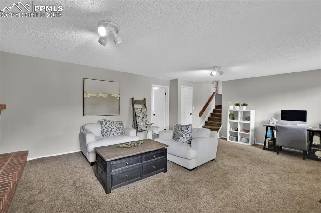 Image 34 of 50: Living area with carpet flooring, a textured ceiling, and stairs
