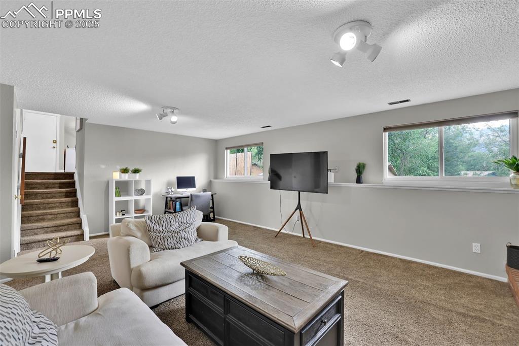 Image 35 of 50: Carpeted living area featuring stairway and a textured ceiling