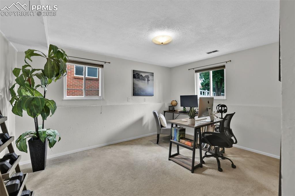 Image 37 of 50: Office with light colored carpet and a textured ceiling