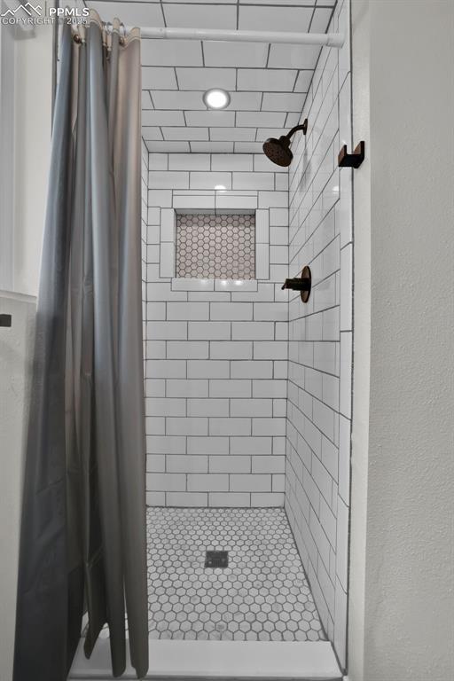 Image 41 of 50: Bathroom featuring a stall shower and a textured wall