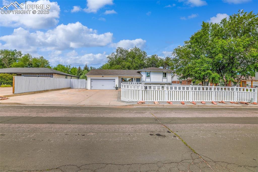 Image 7 of 50: View of front of home with a fenced front yard, concrete driveway, and a ga