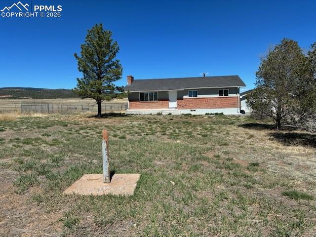 Image 1 of 36: Ranch-style home with a chimney, brick siding, and a view of rural / pastor