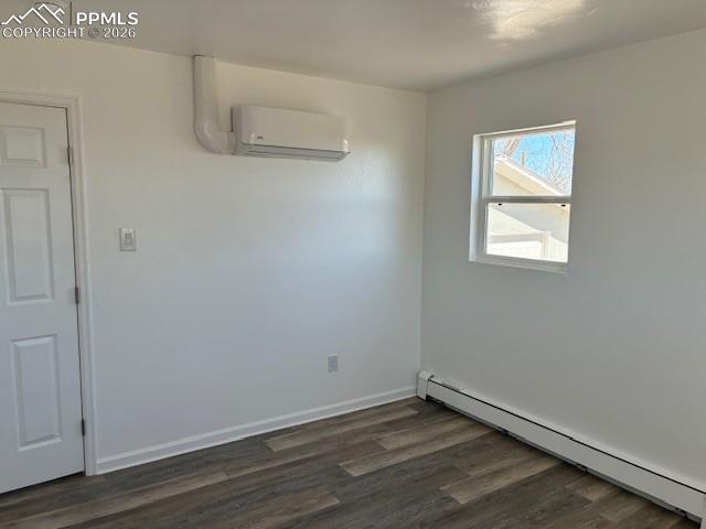 Image 15 of 36: Spare room featuring baseboard heating and dark wood-style floors