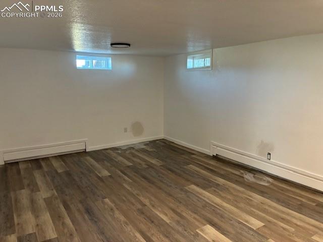 Image 19 of 36: Below grade area featuring baseboard heating, dark wood-style floors, and h