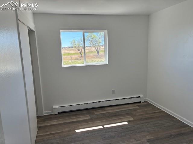 Image 21 of 36: Unfurnished bedroom featuring a baseboard heating unit and dark wood finish