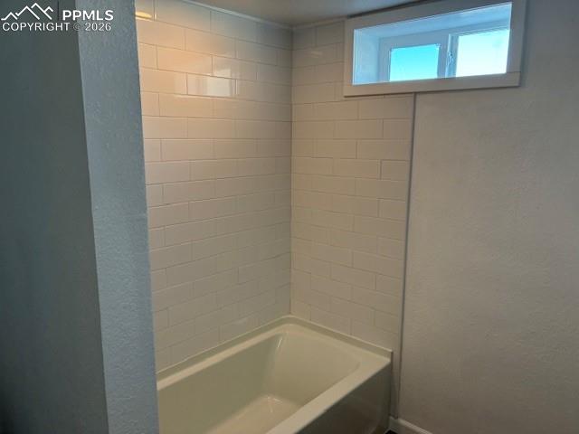 Image 24 of 36: Full bathroom featuring a textured wall and bathtub / shower combination