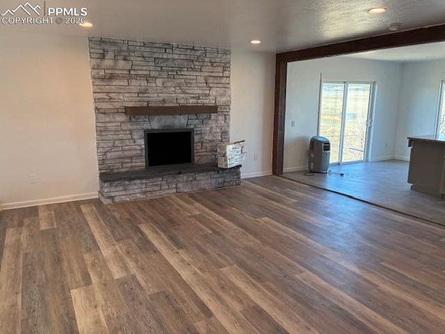 Image 4 of 36: Unfurnished living room with dark wood-style floors, a fireplace, and reces