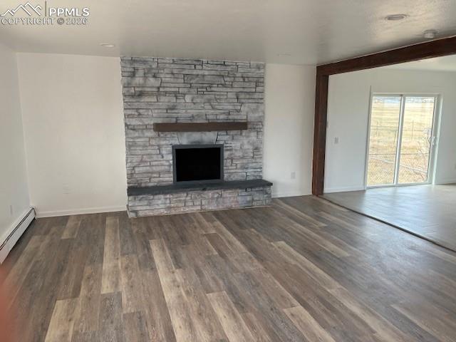 Image 6 of 36: Unfurnished living room featuring dark wood-type flooring and a stone firep