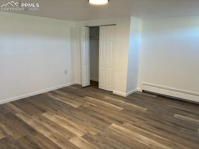 Image 9 of 36: Unfurnished bedroom with a closet, dark wood-style floors, and a baseboard