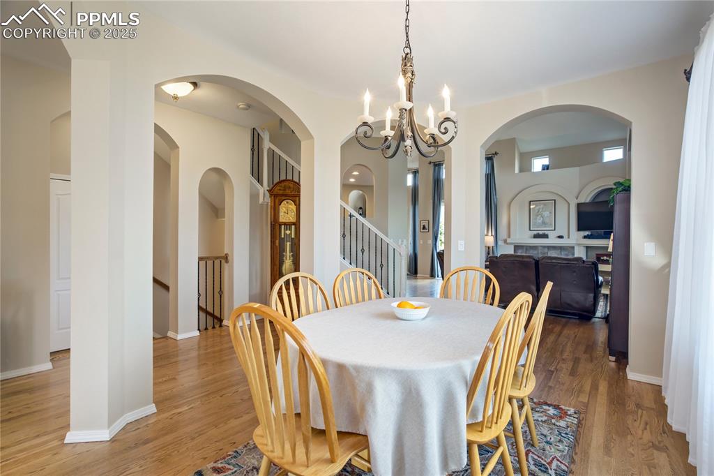 Image 13 of 43: Dining area featuring a chandelier, wood finished floors, and stairs