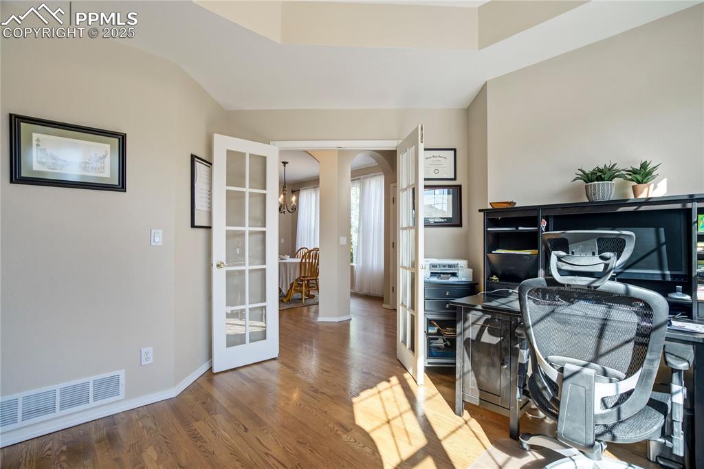 Image 15 of 43: Office area with wood finished floors, a chandelier, french doors, arched w